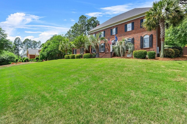 colonial inspired home featuring a front lawn and brick siding
