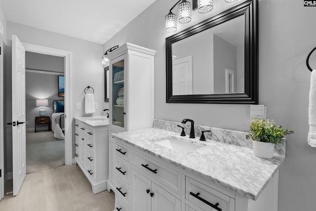 bathroom with wood finished floors, two vanities, a sink, and ensuite bath