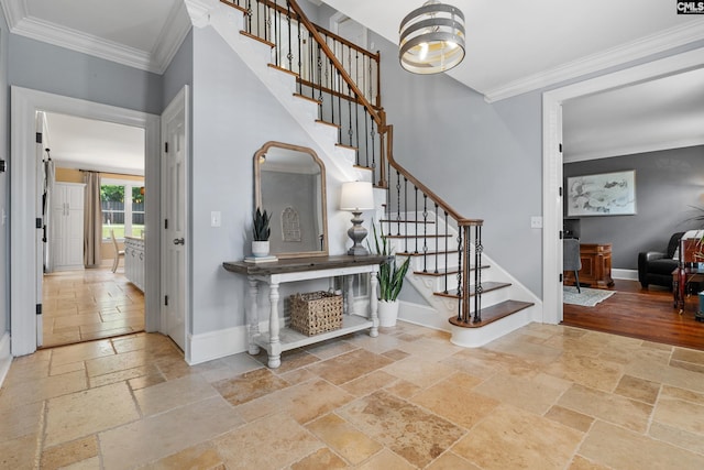 foyer entrance with stairway, baseboards, ornamental molding, and stone tile floors