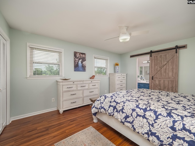 bedroom with a closet, baseboards, ceiling fan, dark wood-style floors, and a barn door
