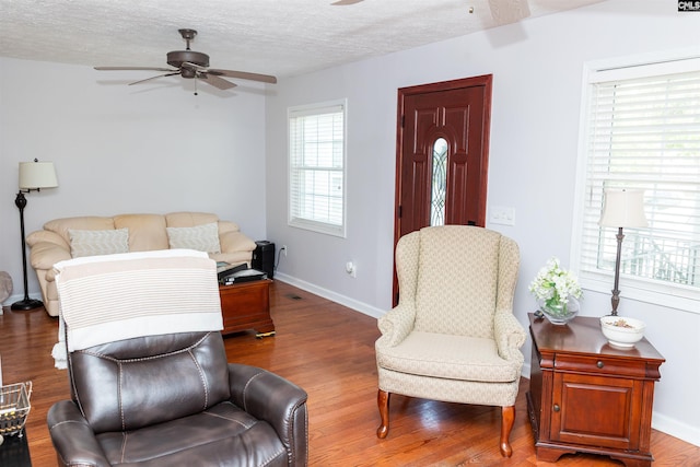 sitting room featuring a textured ceiling, baseboards, a ceiling fan, and wood finished floors