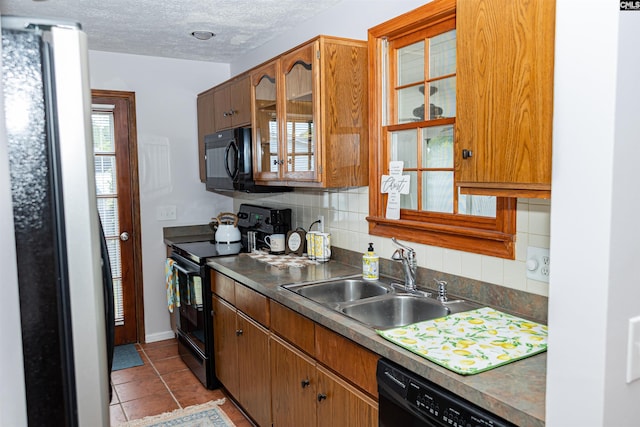 kitchen featuring backsplash, a sink, black appliances, glass insert cabinets, and light tile patterned flooring