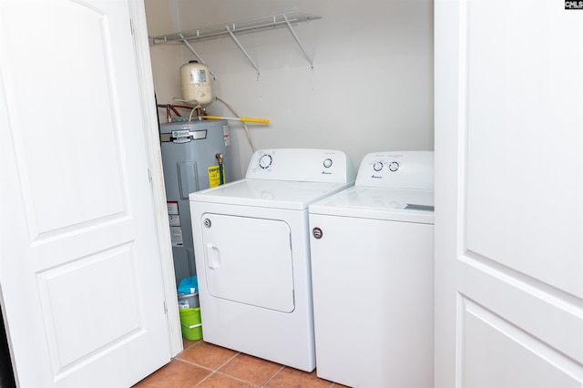 clothes washing area featuring light tile patterned flooring, laundry area, washer and clothes dryer, and electric water heater
