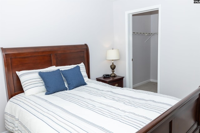 carpeted bedroom with a closet, baseboards, and a walk in closet