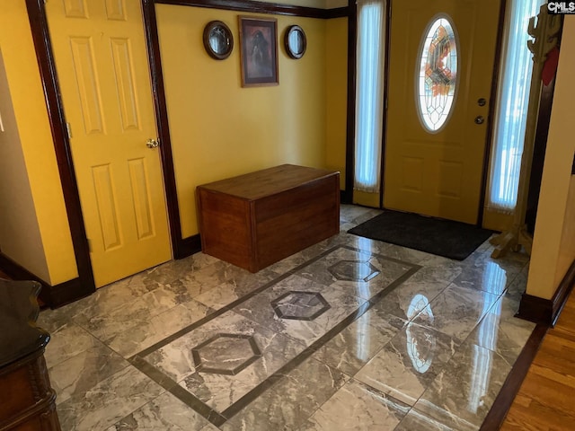 foyer with baseboards and marble finish floor