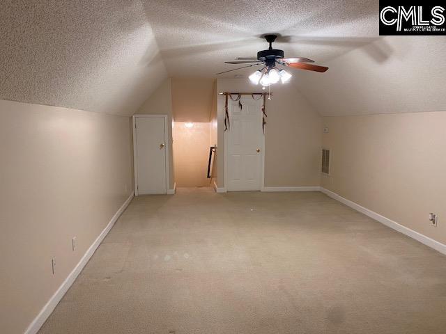 additional living space featuring light colored carpet, a ceiling fan, a textured ceiling, and lofted ceiling