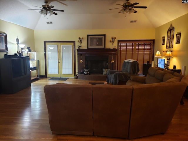 living room featuring a brick fireplace, ceiling fan, wood finished floors, and lofted ceiling