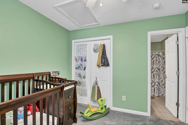 tiled bedroom featuring a nursery area, baseboards, and a closet