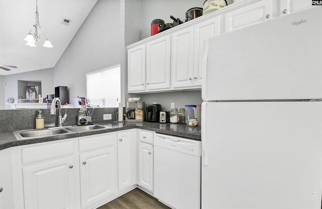 kitchen with dark countertops, white appliances, white cabinets, a sink, and decorative light fixtures