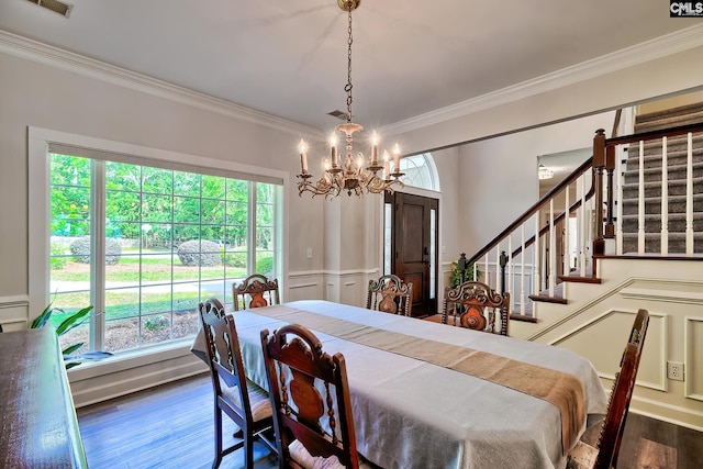dining space with crown molding, a decorative wall, wood finished floors, stairway, and a notable chandelier