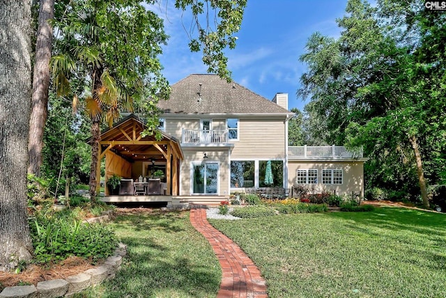 back of property featuring a chimney, a yard, a deck, and a balcony
