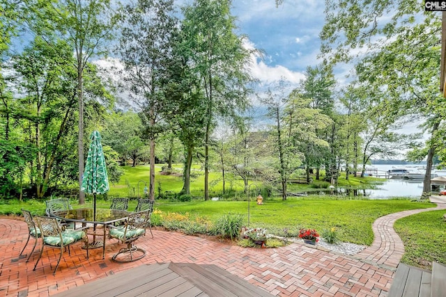 wooden terrace with a patio, a water view, a yard, and outdoor dining space