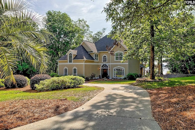 view of front of home with roof with shingles, curved driveway, and stucco siding
