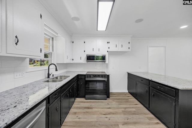 kitchen with dark cabinetry, white cabinetry, appliances with stainless steel finishes, and a sink