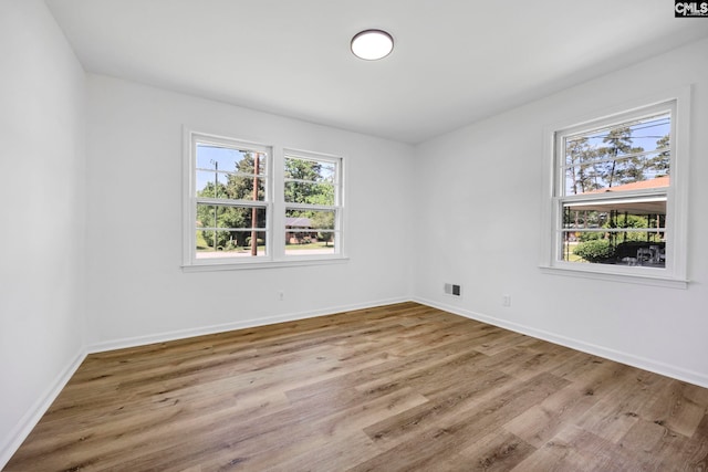 unfurnished room featuring baseboards, wood finished floors, and visible vents