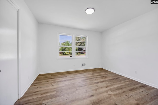 spare room featuring baseboards, visible vents, and wood finished floors