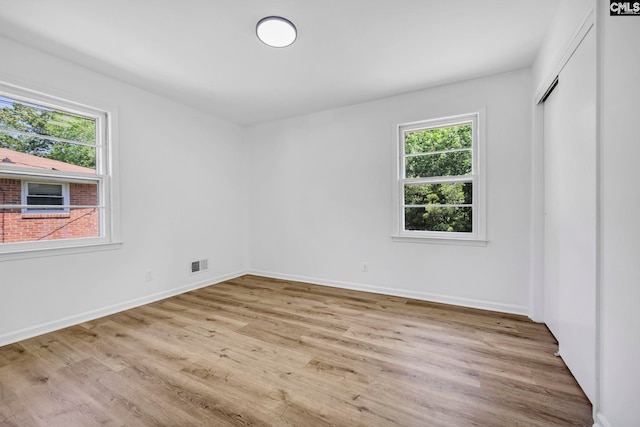unfurnished room with visible vents, plenty of natural light, and wood finished floors