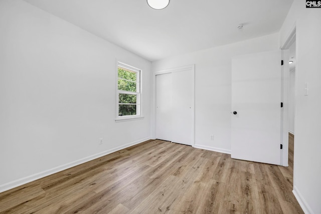 unfurnished bedroom with baseboards, a closet, and wood finished floors