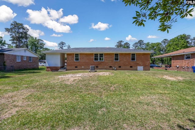 rear view of house with brick siding, a lawn, and crawl space