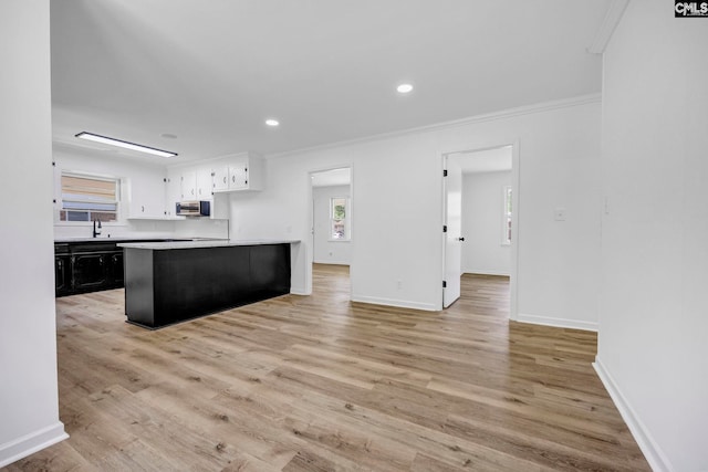kitchen featuring crown molding, stainless steel microwave, a sink, and light countertops