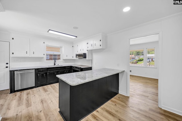 kitchen featuring appliances with stainless steel finishes, light stone countertops, a sink, white cabinets, and a peninsula