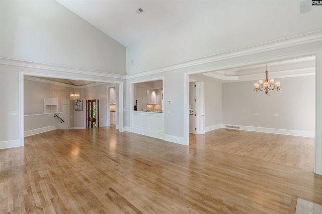 unfurnished living room with visible vents, baseboards, high vaulted ceiling, light wood-style flooring, and a notable chandelier