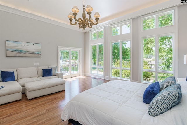 bedroom featuring a towering ceiling, wood finished floors, and a notable chandelier