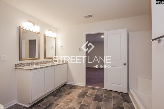 full bath with baseboards, visible vents, a sink, and double vanity
