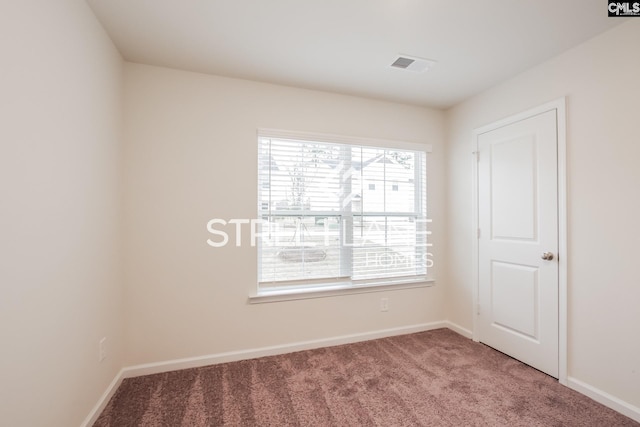 unfurnished room with carpet, visible vents, and baseboards