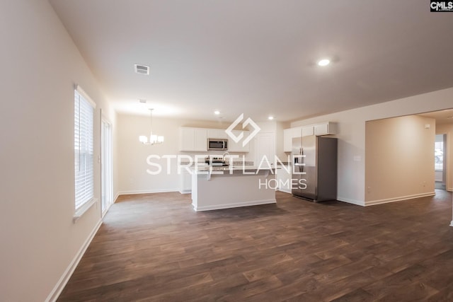 living area with an inviting chandelier, visible vents, dark wood-style flooring, and baseboards