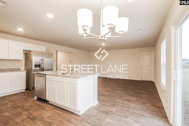 kitchen featuring a notable chandelier, a sink, white cabinetry, stainless steel appliances, and an island with sink