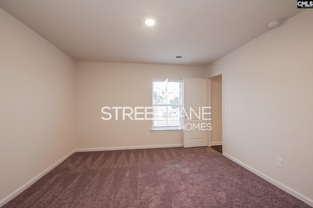 unfurnished room with dark colored carpet and baseboards
