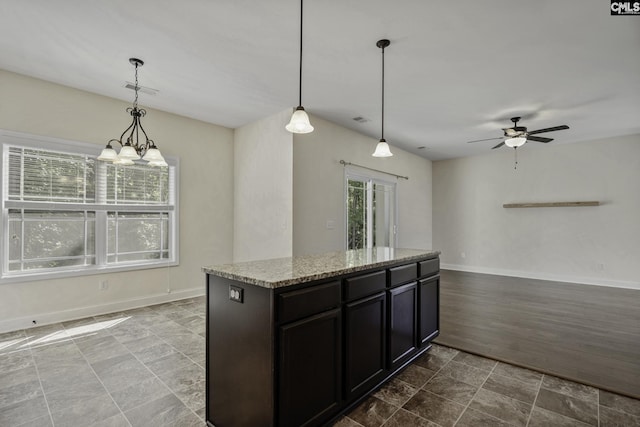 kitchen with baseboards, a ceiling fan, hanging light fixtures, and light stone countertops
