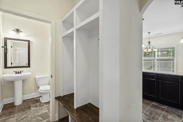 mudroom with baseboards, arched walkways, a sink, and an inviting chandelier
