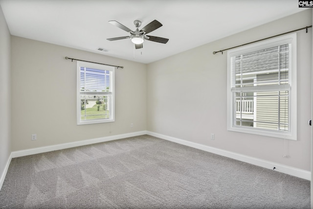 carpeted spare room with baseboards, a ceiling fan, and visible vents