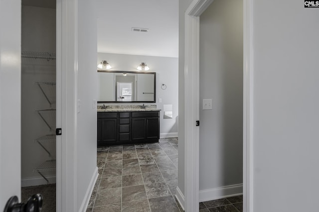 full bathroom with a walk in closet, baseboards, and visible vents
