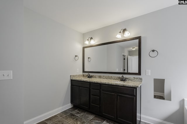 full bath featuring baseboards, a sink, and double vanity