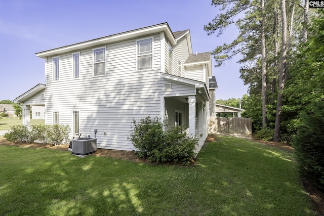 view of side of property with a lawn, central air condition unit, and fence