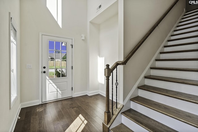 entryway featuring visible vents, a towering ceiling, stairway, baseboards, and hardwood / wood-style floors