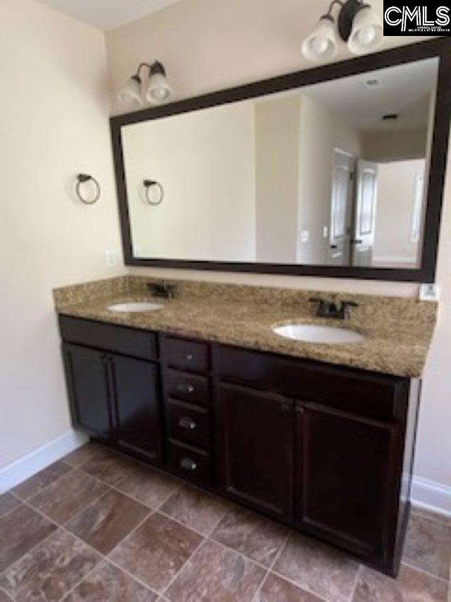 bathroom featuring a sink, double vanity, and baseboards