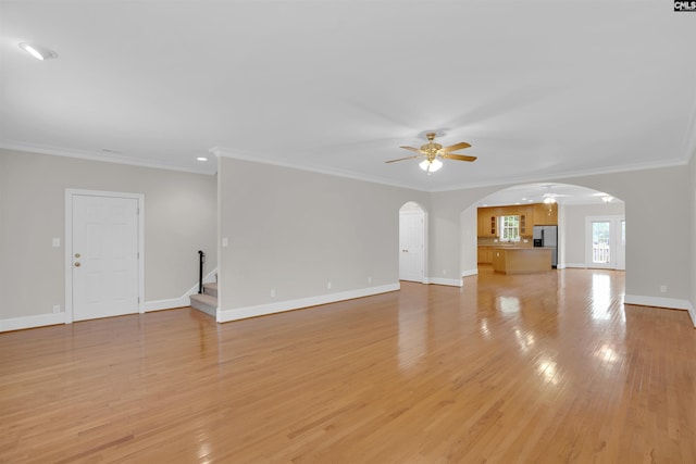 unfurnished living room with arched walkways, stairs, a ceiling fan, baseboards, and light wood-type flooring