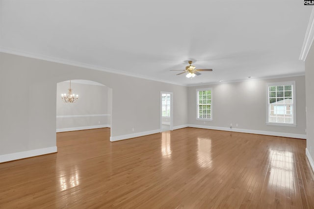 spare room with crown molding, arched walkways, baseboards, and ceiling fan with notable chandelier