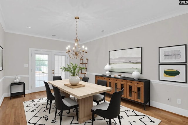 dining space with an inviting chandelier, ornamental molding, baseboards, and light wood-type flooring