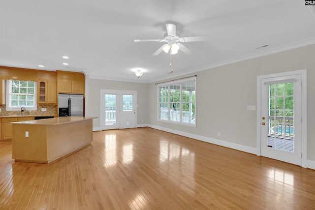 kitchen featuring light countertops, baseboards, light wood-type flooring, a kitchen island, and stainless steel refrigerator with ice dispenser