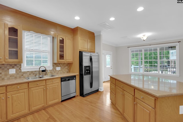 kitchen with a sink, appliances with stainless steel finishes, ornamental molding, and light wood-type flooring