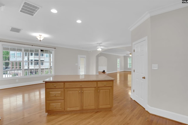 kitchen with ceiling fan, arched walkways, baseboards, visible vents, and ornamental molding