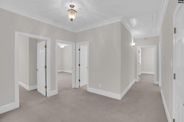 spare room with baseboards, ornamental molding, attic access, and light colored carpet