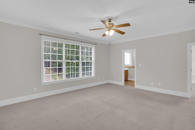 empty room with crown molding, a ceiling fan, baseboards, and light carpet
