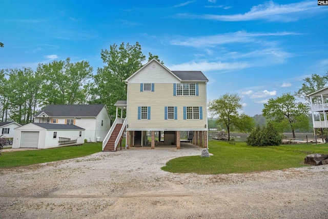 coastal inspired home featuring driveway, an outbuilding, a carport, a front lawn, and stairs