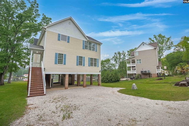 coastal inspired home with a carport, stairs, gravel driveway, and a front yard